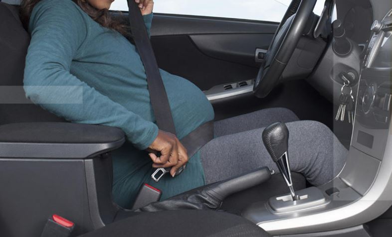 What are the benefits and potential risks of wearing seat belts for pregnant women while driving, and what do the laws in Botswana say about this practice?